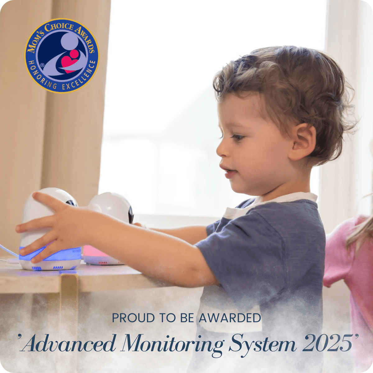 A child's hands reach for two white Babysense Prisma baby monitors, one glowing blue, on a tabletop, with a Mom's Choice Awards emblem visible in the upper left corner and text "Advanced Monitoring System 2025
