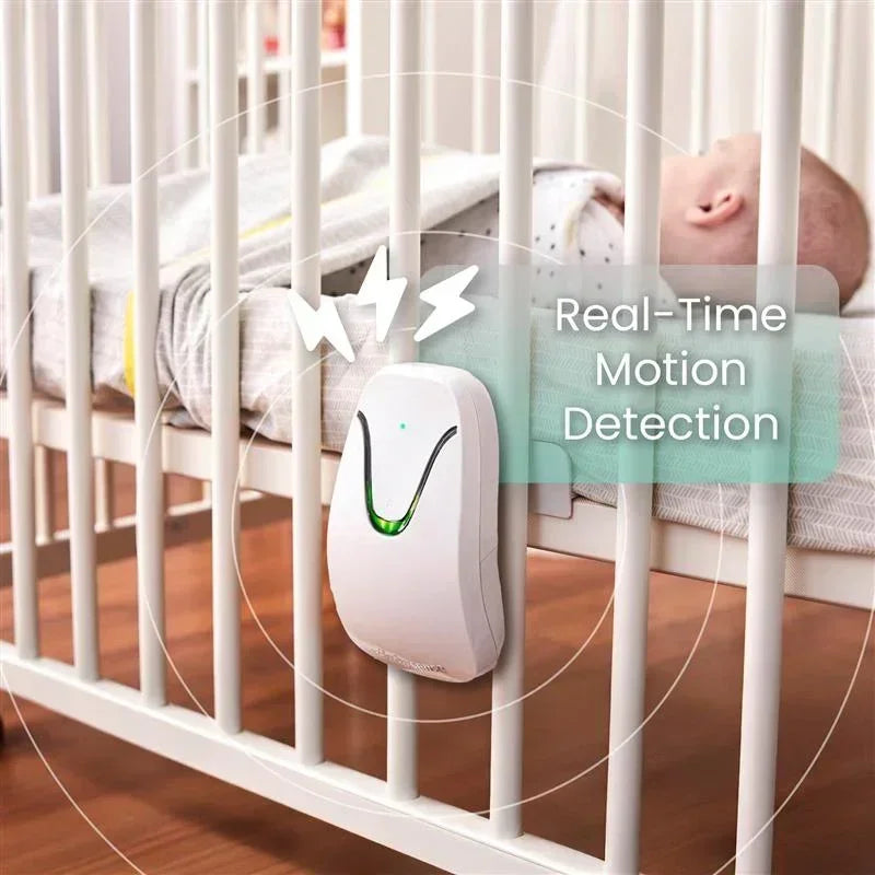 A white Babysense video baby monitor with a green light is attached to a white crib, with a baby sleeping peacefully inside, demonstrating real-time motion detection