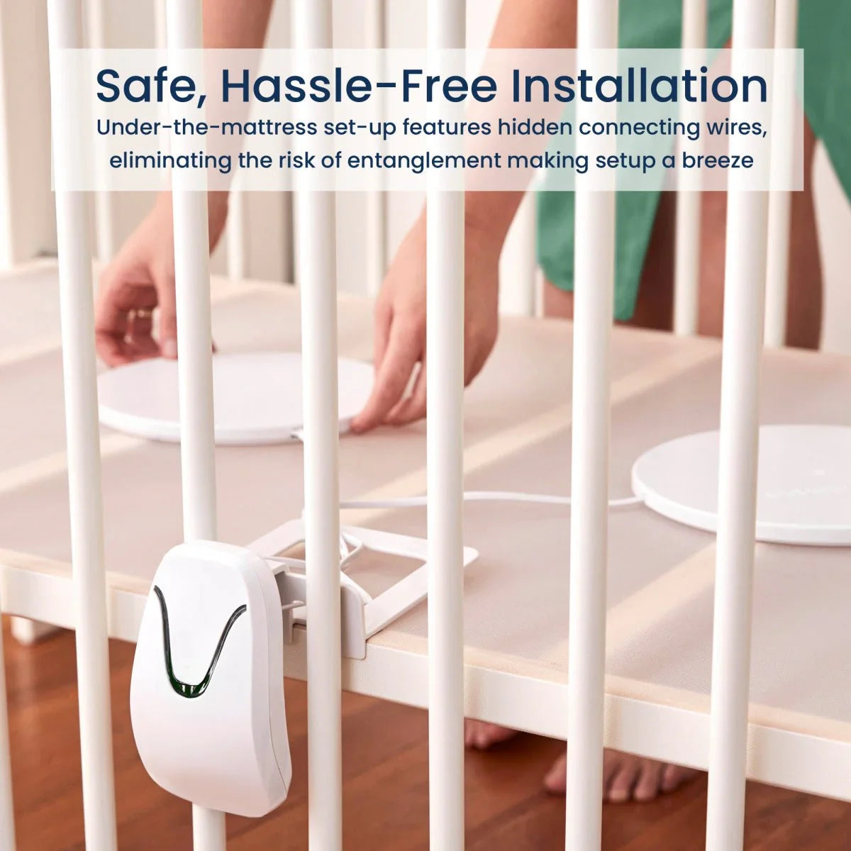 The Babysense Connect Sleep Monitor is installed under a crib mattress, showing two white circular pads and a wall-mounted sensor with a green light, providing a safe, hassle-free installation for a wireless baby monitors full hd