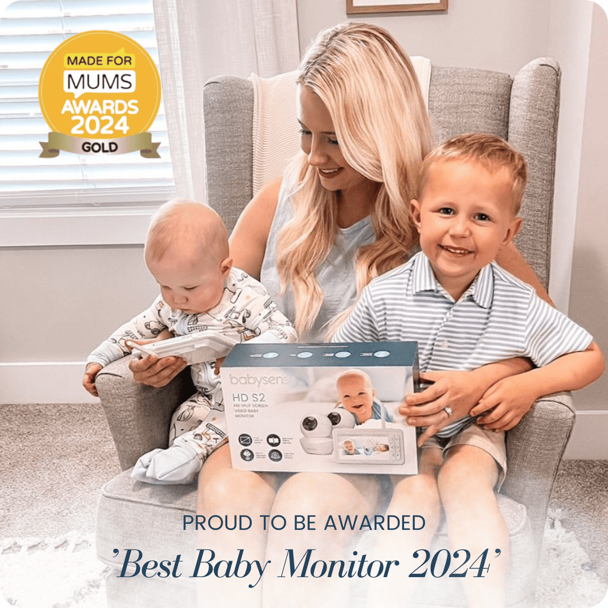 A happy blonde mother smiles next to her two young children, with the Babysense HD S2: Video Baby Monitor with 2 Cameras set, a "Made for Mums Awards 2024 Gold" winner, resting between them