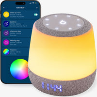 The Babysense Sound & Light Machine, a best baby white noise machine, features a gray fabric base and glowing yellow light, controlled via a dark blue smartphone app with scheduling and color customization options, displaying the time 1:44 in blue on its base