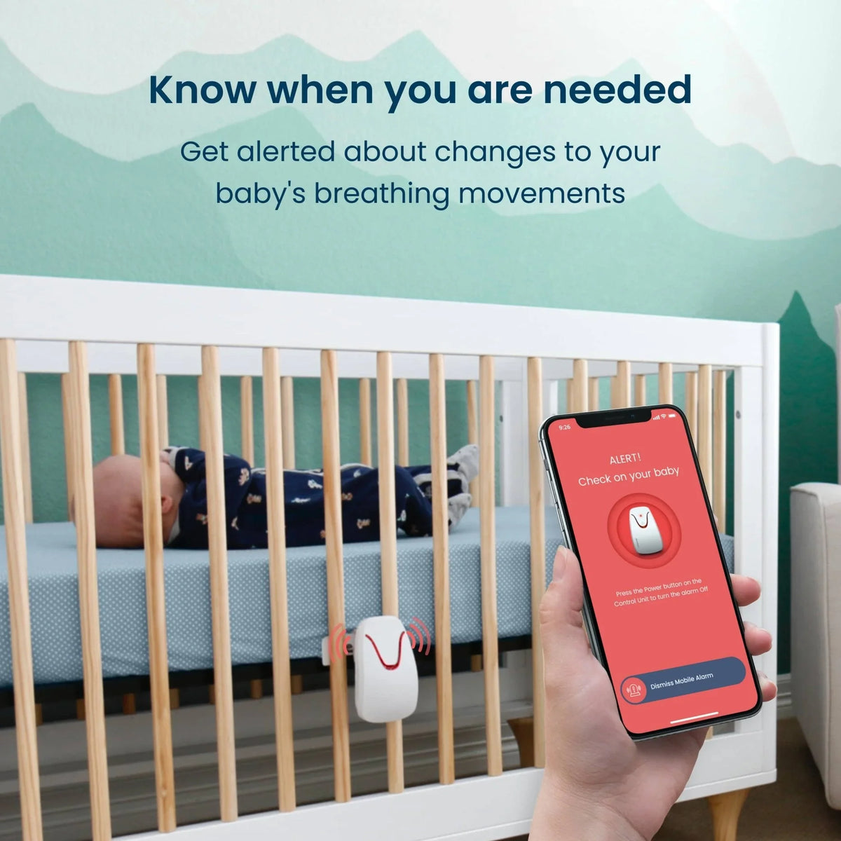 A sleeping baby in a white crib with a Babysense Total Sleep & Monitoring Solution movement sensor on the side, and a hand holding a phone displaying an alert, demonstrating the baby breathing monitor with alarm feature