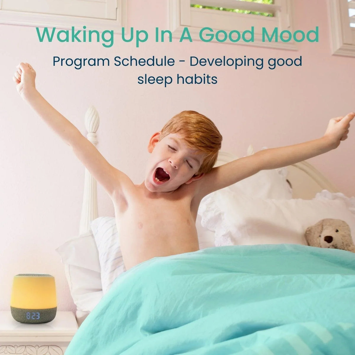 A young boy with red hair yawns and stretches in bed while a Babysense Dreamer 2.0 Night Light & Sound Machine with a visible digital clock sits on his bedside table, though the FullPeek 3MP HD WiFi baby monitor is not visible